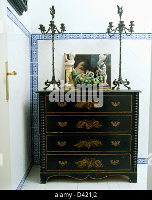 Metal ornamentado candeleros y frutas de cerámica pintada en antigüedades cómoda en el cuarto de baño con azulejos blancos blue+frontera Foto de stock