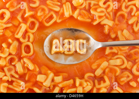 Letras ABC en forma de pasta con una cuchara dentro de cartas en forma de pasta en salsa de tomate Foto de stock