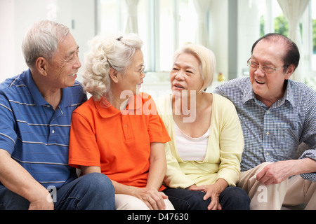 Grupo de Altos amigos chinos relajándose en el sofá en casa