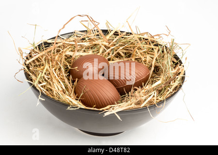 Huevos de pascua en chocolate en el cuenco de paja Foto de stock