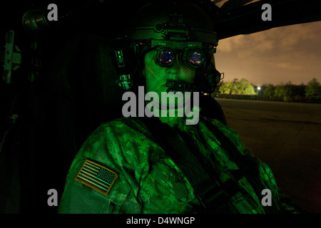Un piloto equipado con gafas de visión nocturna en la cabina de un helicóptero Apache AH-64. Foto de stock
