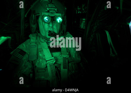 Un piloto equipado con gafas de visión nocturna en la cabina de un helicóptero Chinook CH-47. Foto de stock