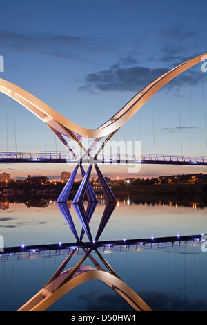 El puente Infinito, Stockton-on-Tees, reflejado en el río Tees al atardecer. Foto de stock