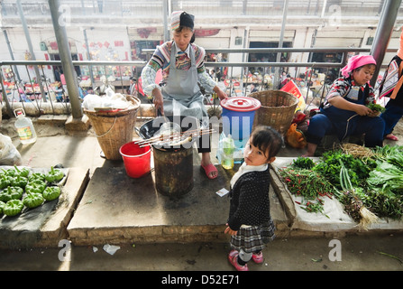 Niño de espera para ser atendido en un puesto de comida en el mercado Yuanyang en la provincia de Yunnan, en China