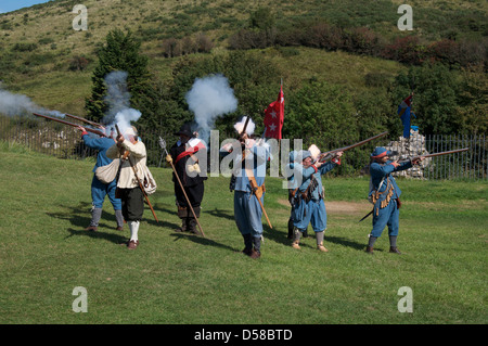Un grupo de guerra civil inglesa re-enactors en los uniformes de los mosqueteros monárquico disparar sus armas. El castillo Corfe, en Dorset. Inglaterra, Reino Unido" Foto de stock