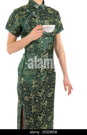 Mujer en verde y dorado vestido chino sostiene una taza de té.