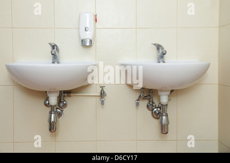 Dos lavabos y jabón líquido blanco en aseo público Foto de stock