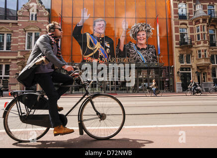 Países Bajos, Amsterdam, 27 de abril de 2013.Un ciclista pasa por los retratos de la Reina Beatriz de los Países Bajos y de su hijo, el Príncipe Willem-Alexander, aparece delante de un teatro en Amsterdam el 27 de abril de 2013. Amsterdam, la capital de los Países Bajos está preparando para el día de la Reina el 30 de abril, que también marcará la abdicación de la reina Beatriz y la investidura de su hijo mayor, Willem-Alexander. Alamy Live News Foto de stock