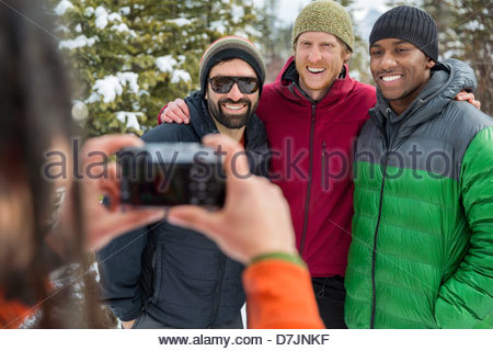 El hombre tomando fotografías de amigos fuera en invierno
