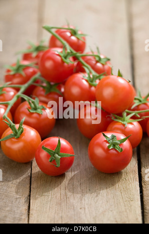 Cierre de una cadena de vid tomates cereza madura sobre una mesa de madera rústica.