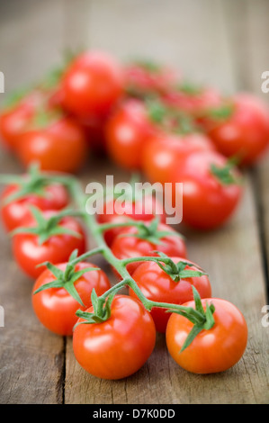 Cierre de una cadena de vid tomates cereza madura sobre una mesa de madera rústica.
