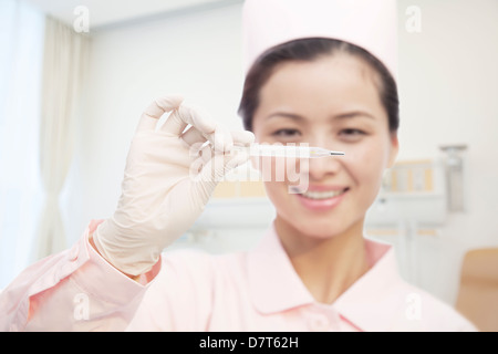 Joven enfermera celebración Termómetro, en primer plano