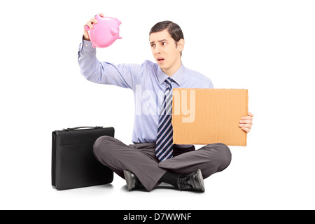 Mal empresario sosteniendo una caja de dinero vacía y un pedazo de cartón, aislado sobre fondo blanco. Foto de stock