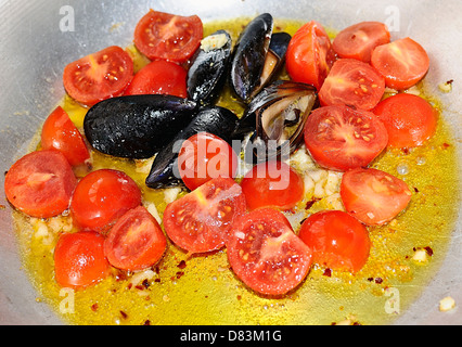 Cazuela con mezcla de mejillones, tomate, ajo y aceite Foto de stock