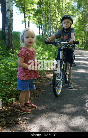 Los niños el hermano y la hermana en la trayectoria de la bici, el horario de verano, los hermanos Foto de stock