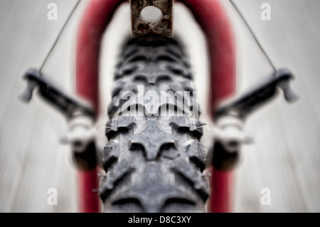 Una llanta y neumático delantero desenfocado mecanismo de freno de la bicicleta de montaña que muestra la banda de rodadura y el desenfoque de movimiento simétrico. Foto de stock