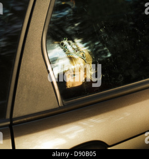 Una chica escandinava con una corona en su cabello mirando desde una ventana de coche, Suecia.