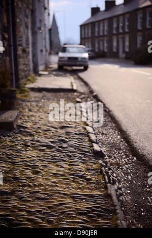 Piedras colocadas en patrones lineales y espiguilla para formar el pavimento y canalones fuera de una terraza de casas, Llanrhystud, Gales, Reino Unido.