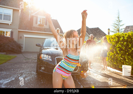 Joven baila mientras la familia se lava el coche en el garaje de su casa en una soleada tarde de verano en Portland, Oregón, EE.UU.