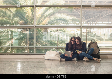 Las adolescentes sentados en el piso con la tableta digital