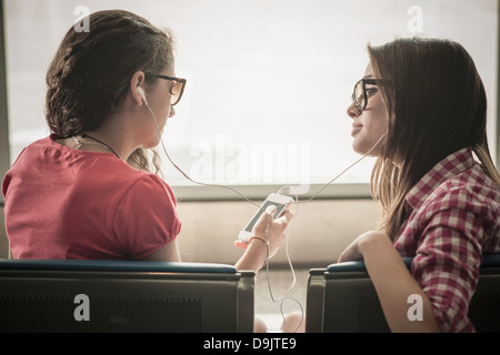 Dos chicas adolescentes con gafas de sol escuchando música Foto de stock