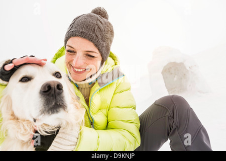 Mujer en tejer hat acariciarle la cabeza de perro