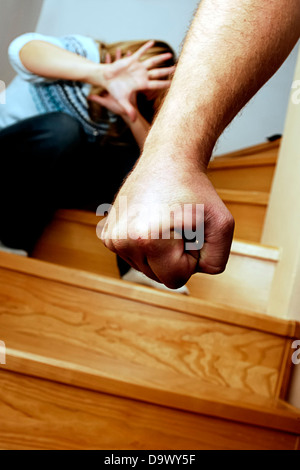 Hombre mano amenazadora con un miedo mujer agazapado en el fondo - concepto de violencia doméstica