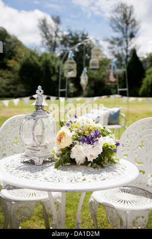 Jardín decorado para la recepción de la boda con bunting, linternas y jaulas de aves en una vendimia shabby chic tema con bouquet Foto de stock