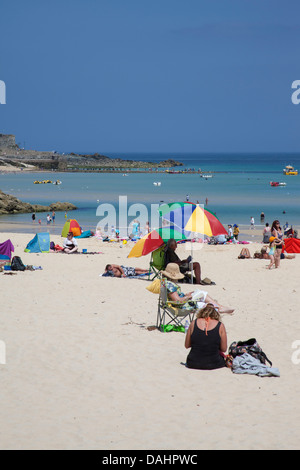 La gente relajándose en la playa de St. Ives Cornwall Porthminster playa personas refugiadas procedentes del sol bajo las sombrillas Foto de stock