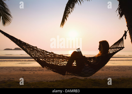 Silueta de mujer, relajarse en una hamaca en la playa
