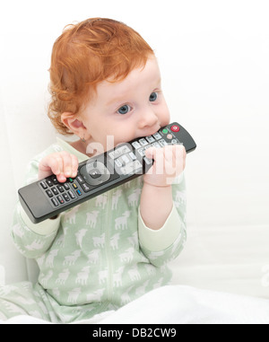 Bebé niño viendo televisión sosteniendo el control remoto
