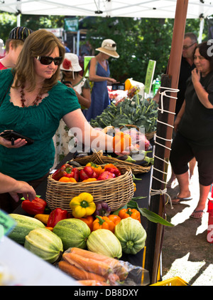 mercado Domingo dh Bahía hawkes HASTINGS NUEVA ZELANDA Señora recogiendo verduras verdes comestibles puesto alimentos de frutas de la fuente Foto de stock
