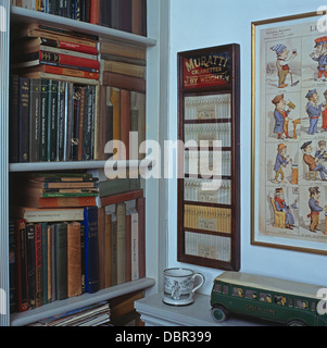 Los libros en los estantes con trompe-l'oeil libro junto a cigarrillos Muratti paneles enmarcados en la sala pequeña Foto de stock