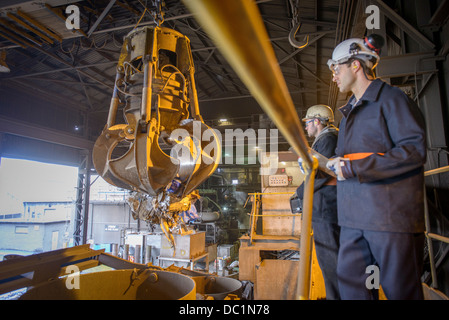 Los trabajadores viendo pinza mecánica en fundición de acero