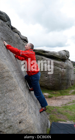 Escalador Doug Blane trepar rocas al borde Burbage South, Derbyshire Peak District National Park, Inglaterra, Reino Unido.