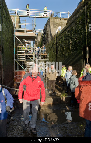 La gente dentro de una cámara de bloqueo drenado, recorriendo y mirando el trabajo de renovación - Jornada de puertas abiertas, Bingley cinco bloqueos de subida, West Yorkshire, Inglaterra, Reino Unido.