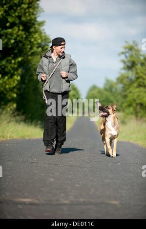 Mujer corriendo con un perro Pastor Belga Malinois o Foto de stock