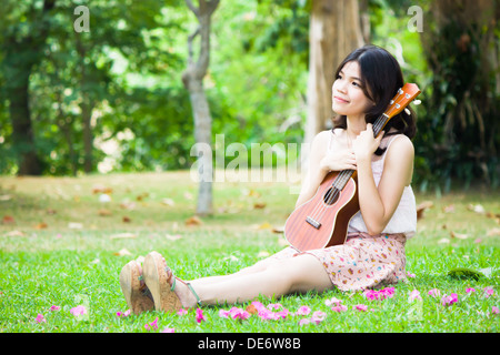 Chica asiática con ukelele guitarra en el jardín al aire libre Foto de stock