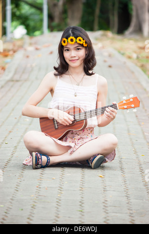 Chica asiática con ukelele guitarra outdoor en concepto feliz Foto de stock