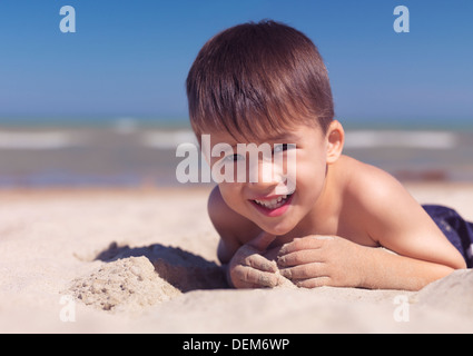 Retrato de un lindo niño feliz jugando en la arena de la playa. El lago Huron, en Ontario, Canadá.