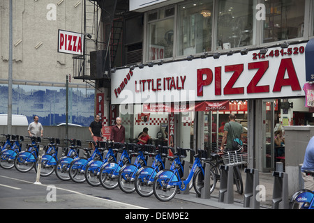 Citi Bikes está junto a Little Italy Pizza en 33rd St & 5th Avenue en Nueva York. Foto de stock
