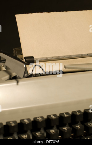 Vintage typewriter con hoja de papel en el interior sobre fondo negro.