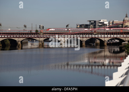 Vista al oeste para ferrocarriles, carreteras y puentes peatonales sobre el río Clyde en el centro de la ciudad de Glasgow, Escocia, Reino Unido Foto de stock