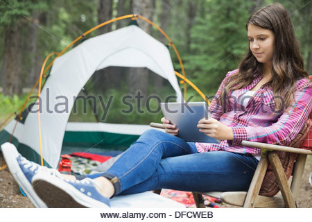 Adolescente mediante tableta digital en camping