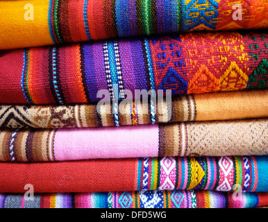 Una pila de coloridas y los textiles andinos tradicionales a la venta en un mercado en Cusco, Peru. Foto de stock