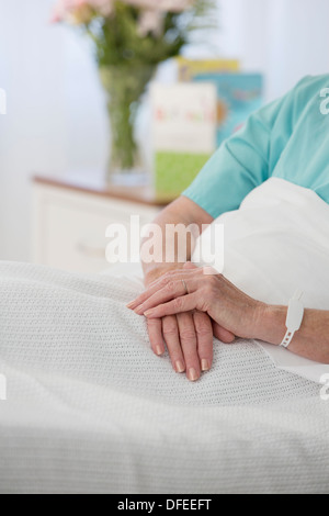 Cerrar senior de manos del paciente en la cama del hospital Foto de stock