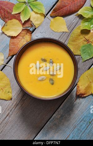Tazón de Sopa de calabaza sobre mesa de madera rústica.