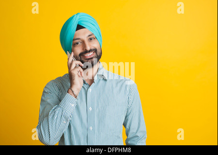 Sikh hombre hablando por un teléfono móvil y sonriendo Foto de stock