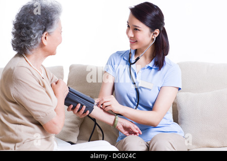 Auxiliar de enfermería teniendo altos la presión arterial de la mujer Foto de stock