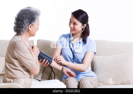 Auxiliar de enfermería teniendo altos la presión arterial de la mujer Foto de stock